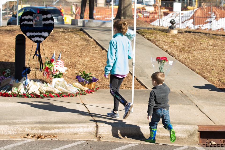 Young boy and girl carry flowers to memorial