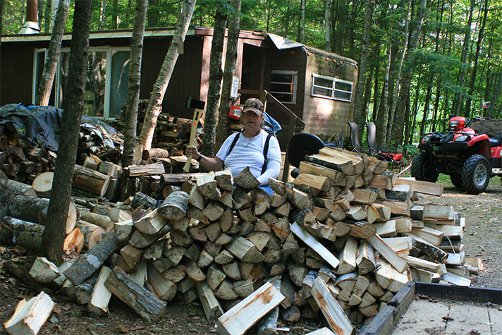 Gary Hand sitting behind woodpile