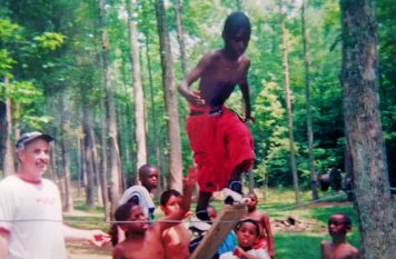 James Ahrendt watching young boy climb up board