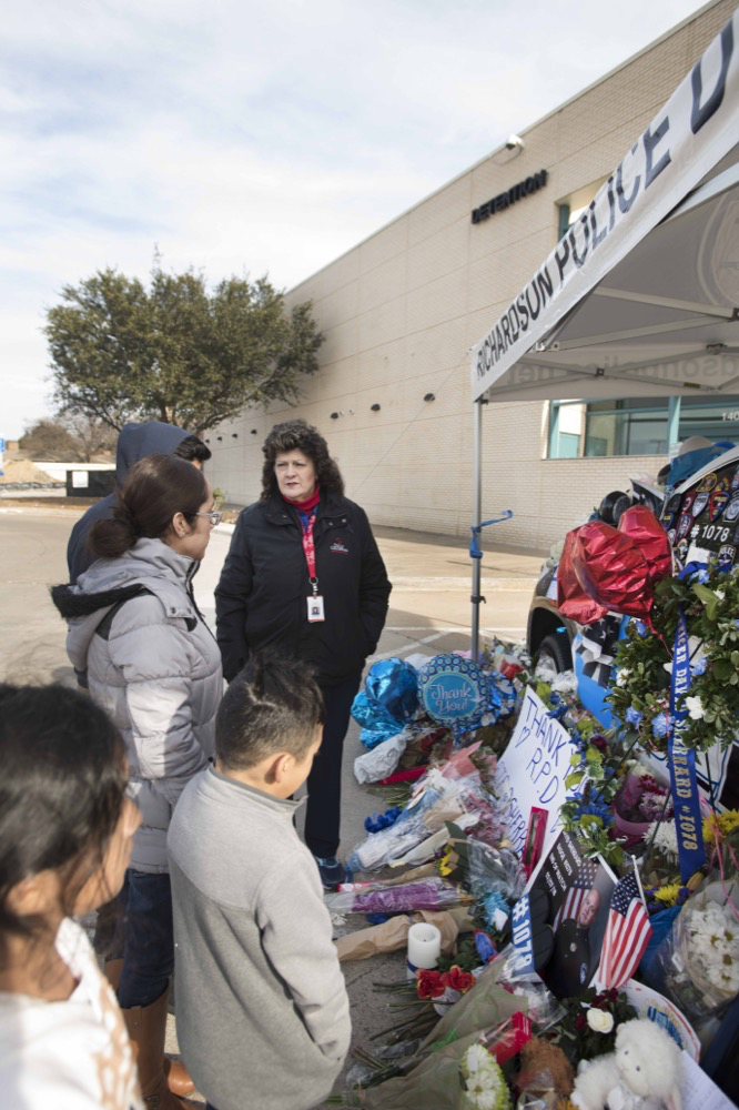 Chaplains talk to a family at a memorial site for fallen police officer David Sherrard in Richardson, Texas