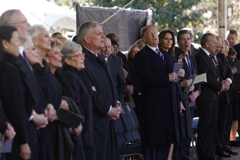 President Donald Trump listens at the funeral