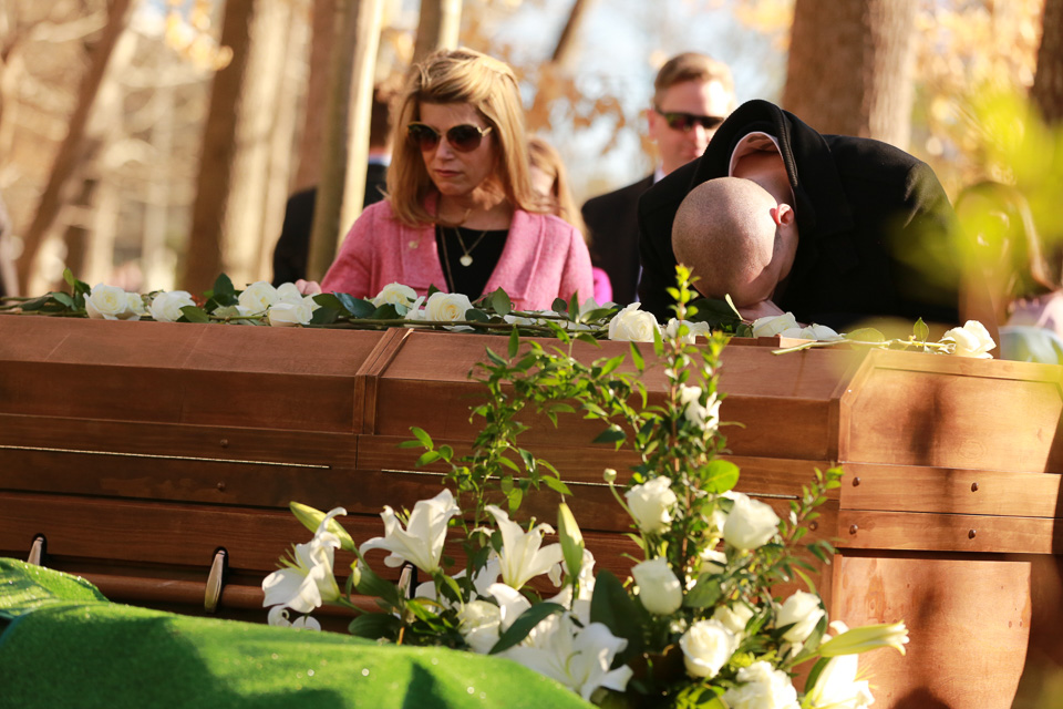 Woman and man with his head bowed on Mr. Graham's casket
