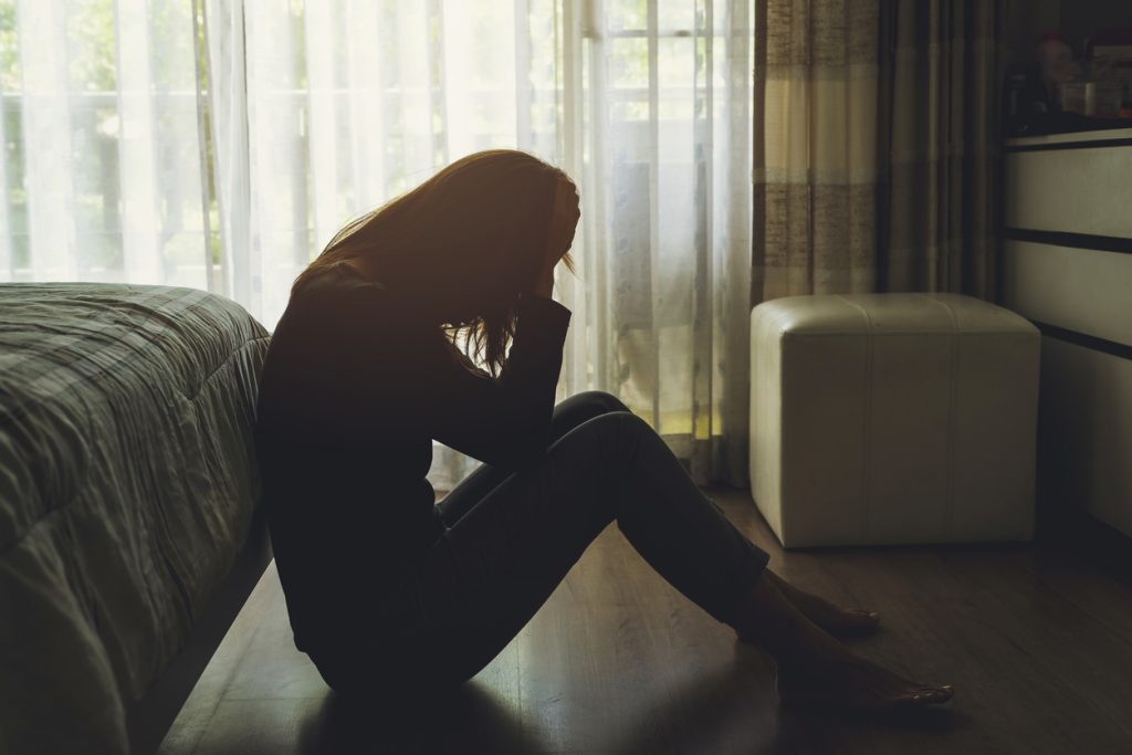 woman sitting on floor with head in hands