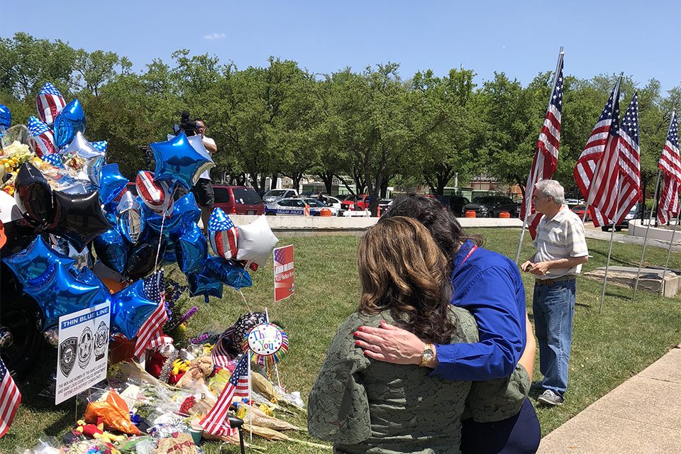 Female chaplain prays with woman in front of a memorial