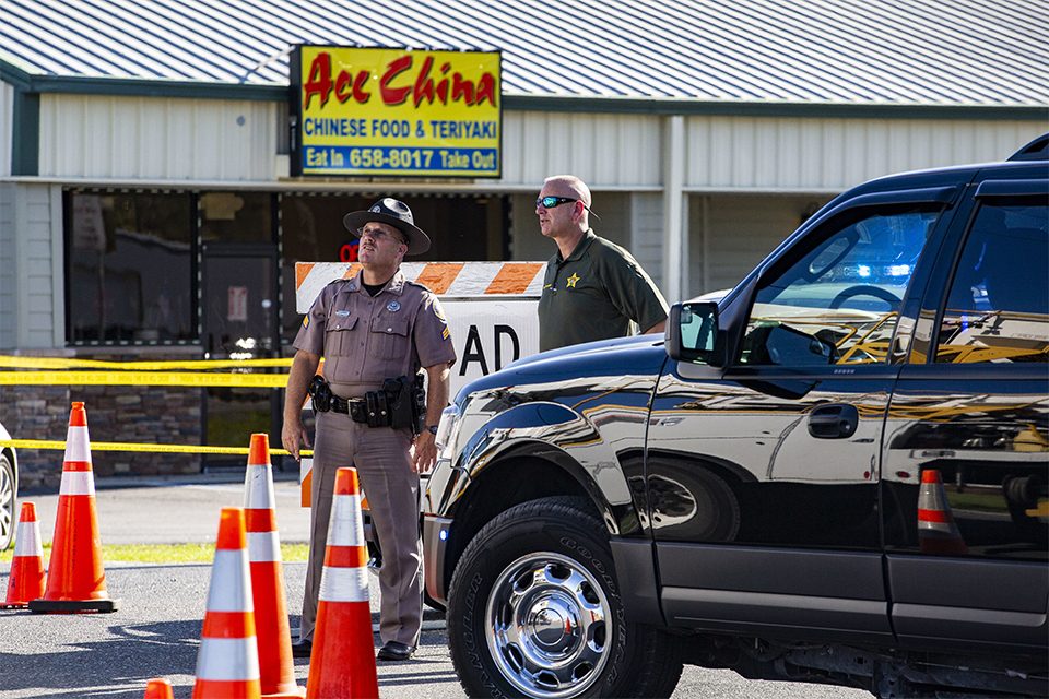 Two police officers in front of Chinese restaurant, looking up at helicopter