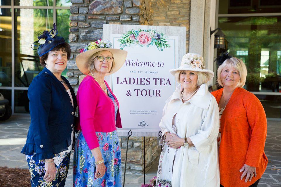 Four women stand in front of the welcome sign