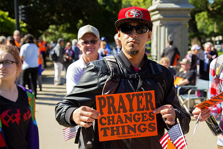 Man holds sign that says, "Prayer Changes Things"
