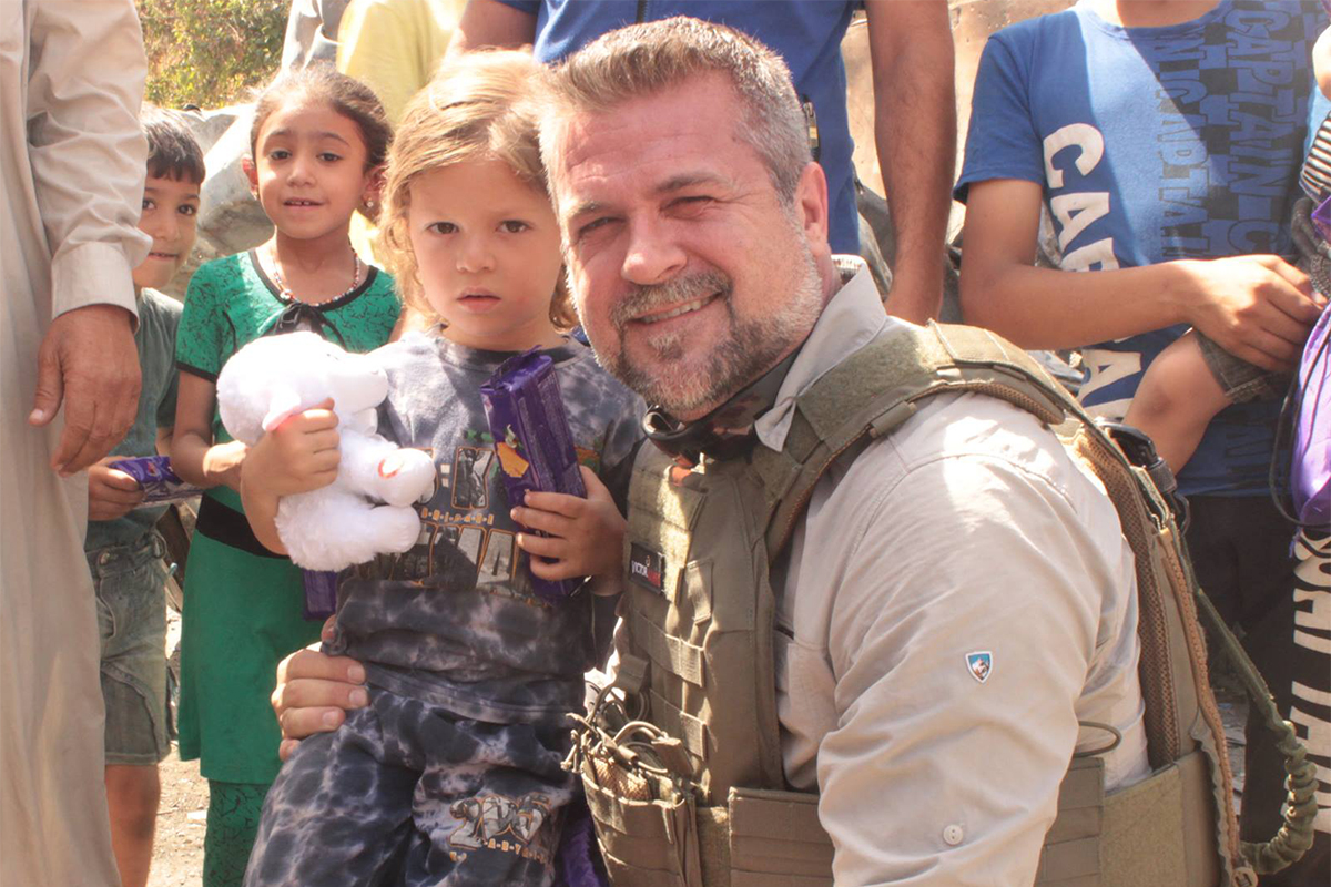 Wearing bullet proof vest with child holding lamb-1200×800