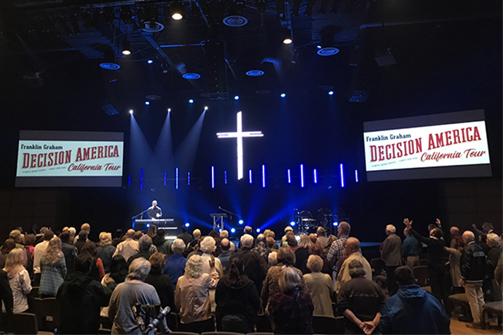 People worshiping inside church; Decision America California signs
