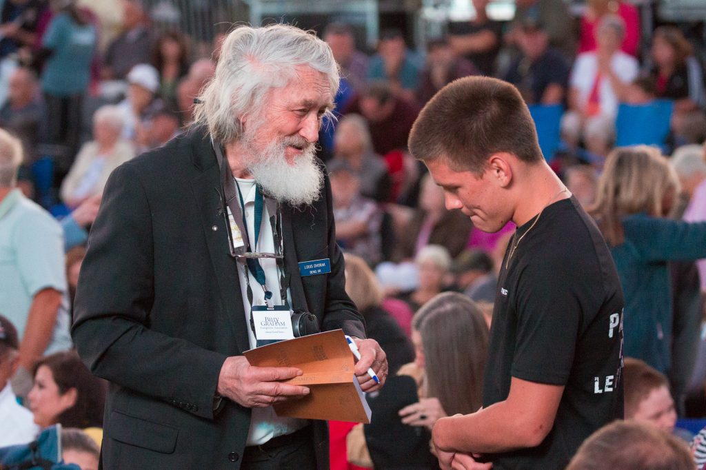 Man giving Bible to young man