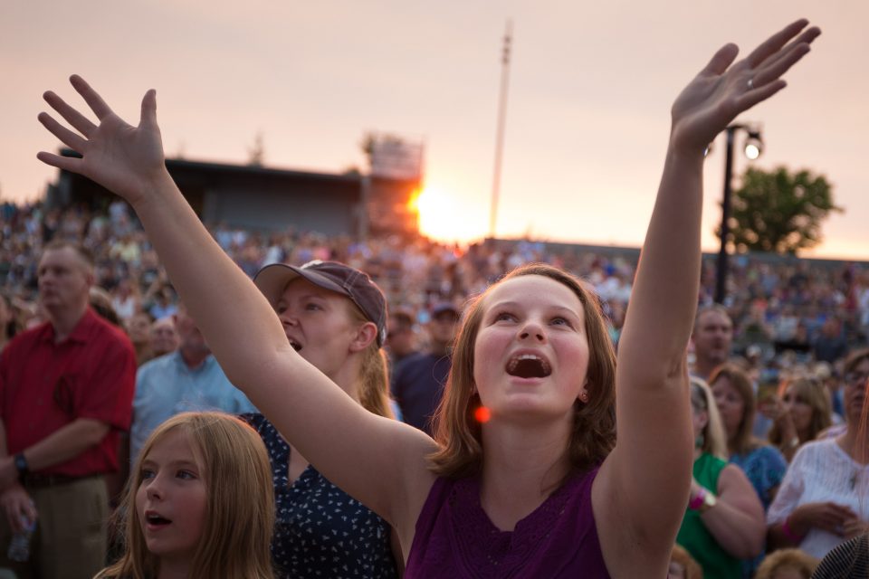 young woman with arms raised in crowd