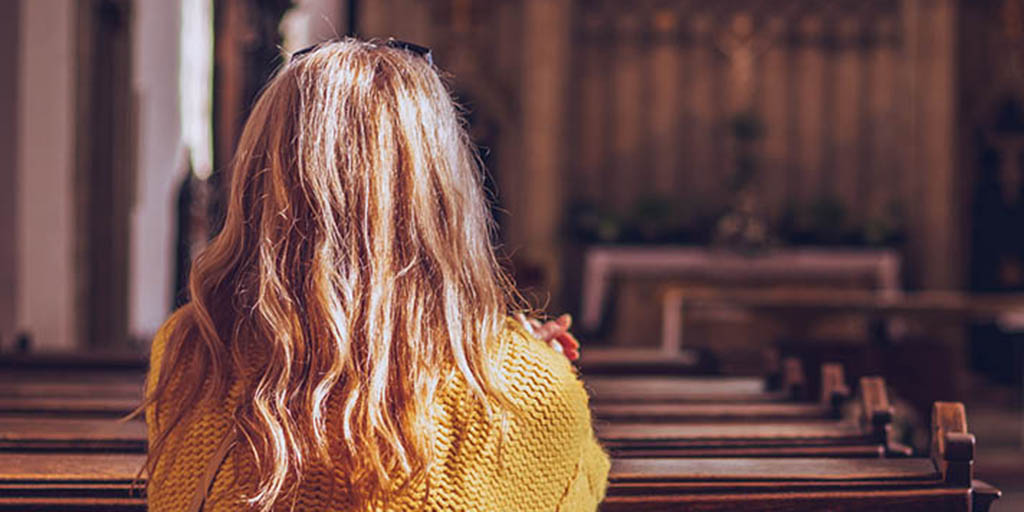 Young woman praying and meditating in church. Catholic cathedral with ...