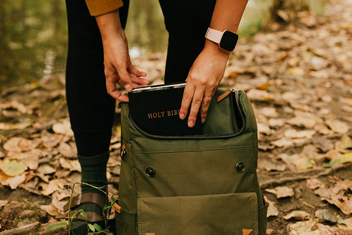 woman taking Bible out of backpack
