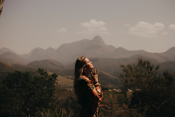 Girl clasping hands in prayer with backdrop of mountains