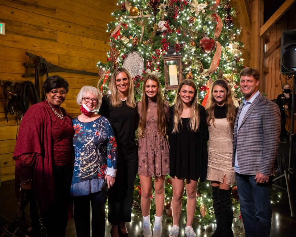 Two guests, Rachel-Ruth Wright and family in front of Christmas tree