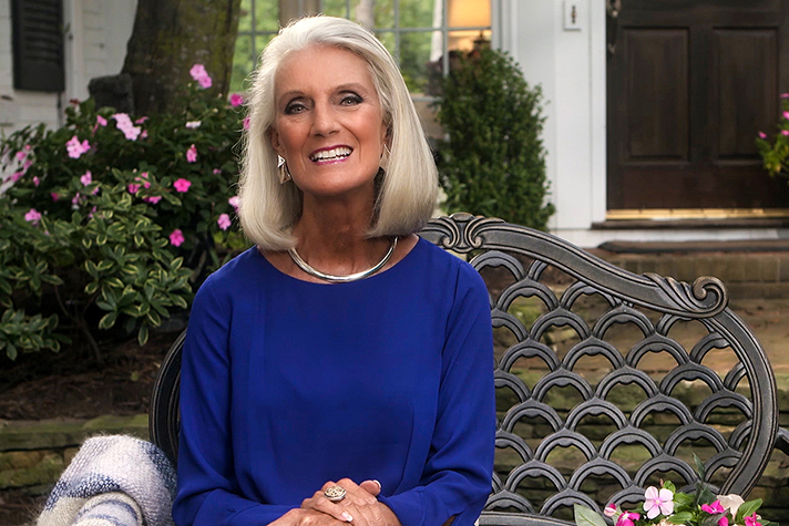 Anne Graham Lotz sitting on a bench in front of flowers