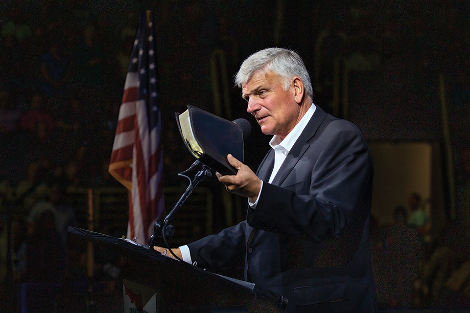 Franklin Graham holding a Bible at podium