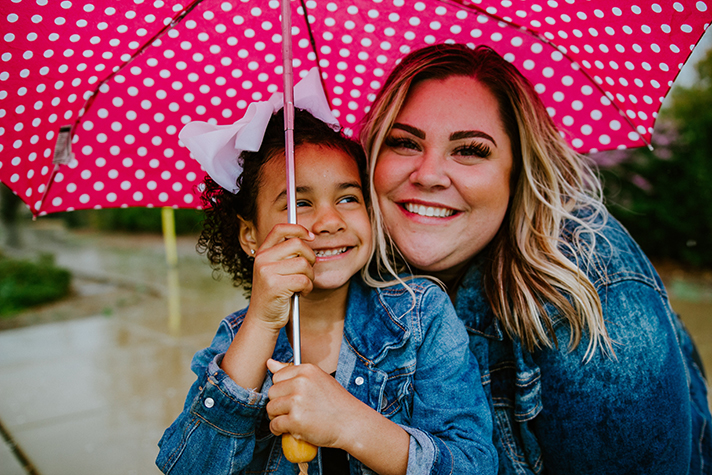 woman with young girl holding pink umbrella
