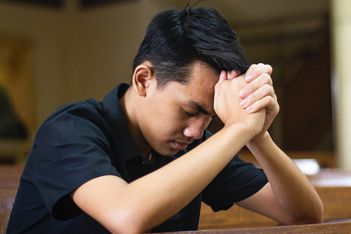 Young man praying with hands clasped