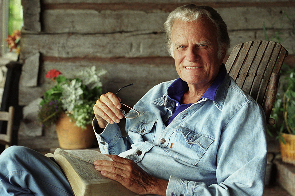 Billy Graham with open Bible in rocking chair