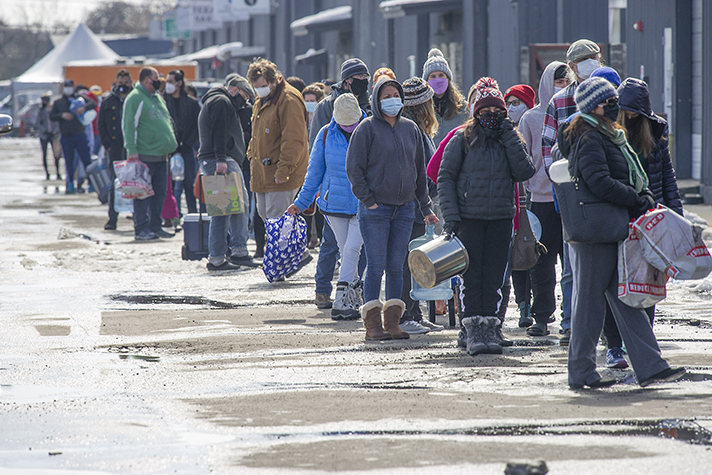 People dressed in warm clothes, standing in line outside