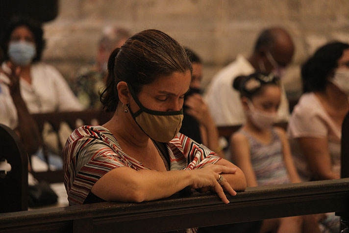 Woman with mask on praying with others in church