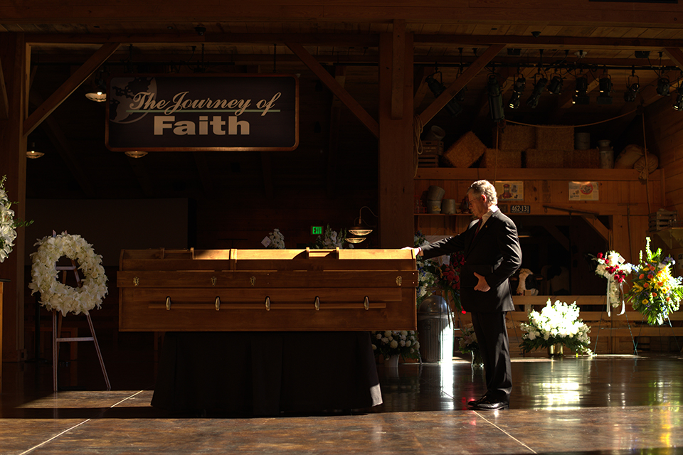 Dr. Don Wilton touching Billy Graham's casket with head bowed