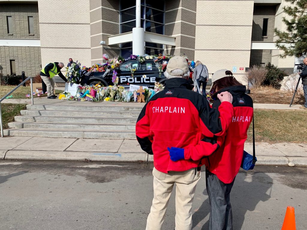 Chaplains hold each other at officers' memorial site