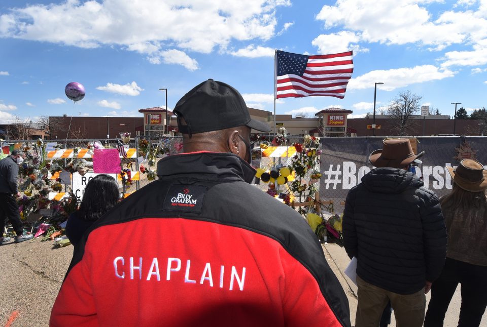 Chaplain with back to camera, looking at memorial