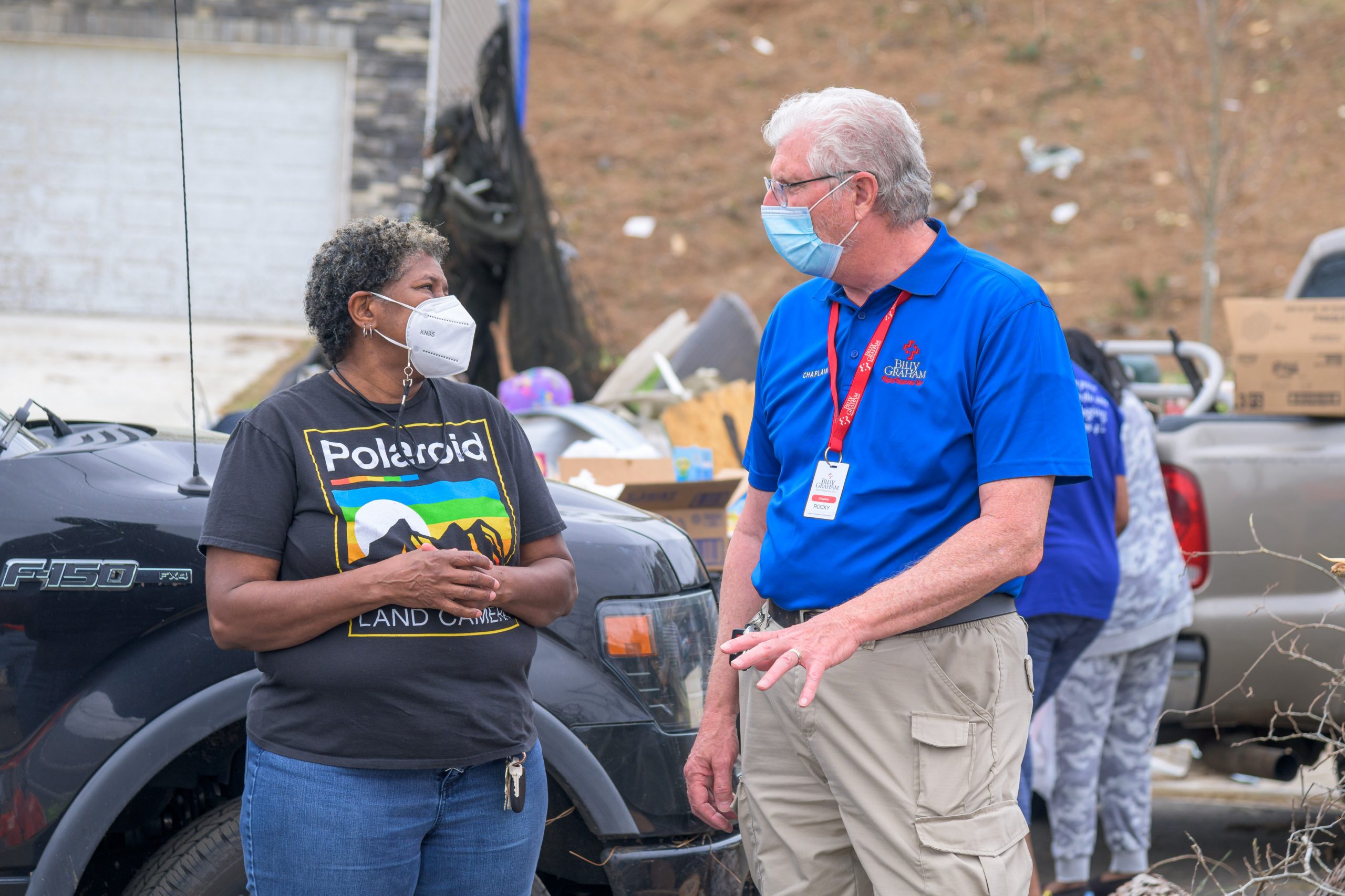 A chaplain talks with a smiling masked woman