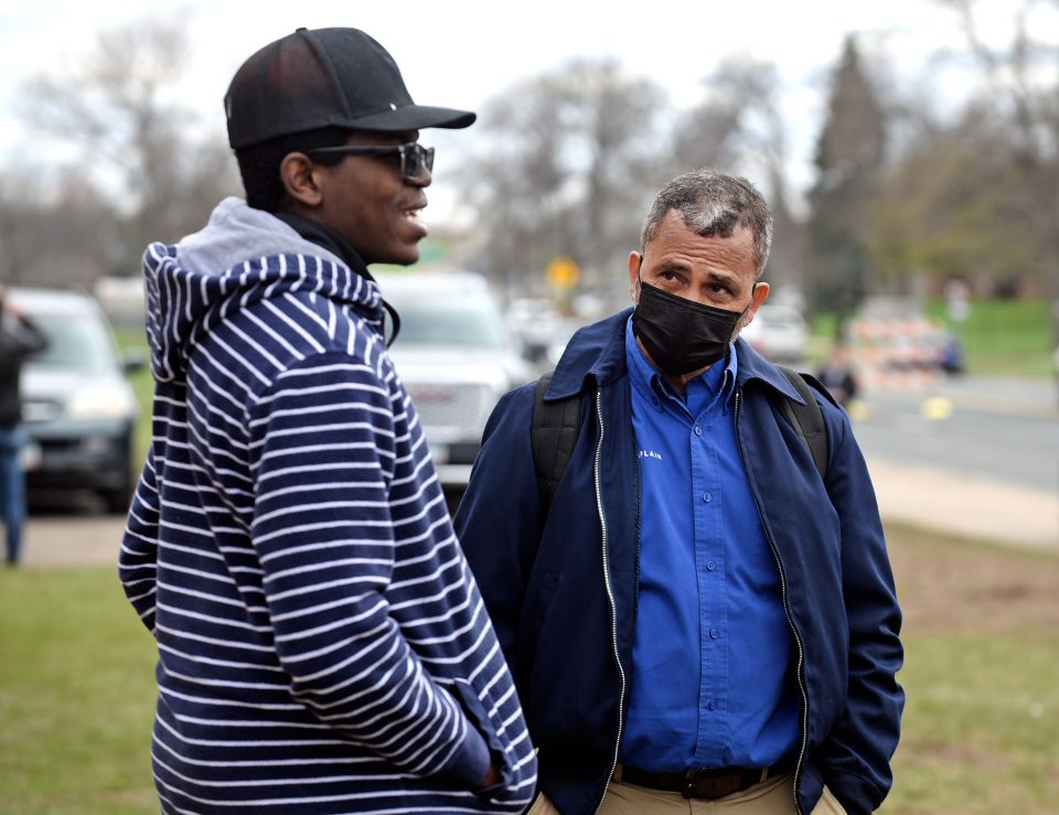 A chaplain talks with a man in a black baseball cap and striped jacket