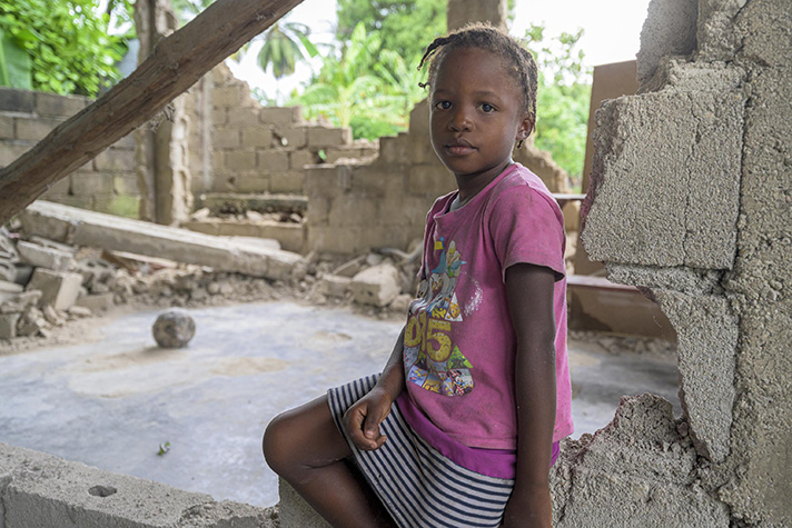 Young Haitian girl sits amid rubble