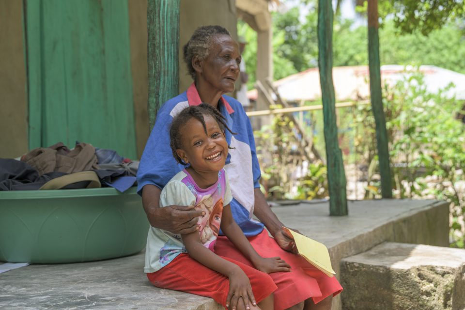 Child smiling, sitting with older woman
