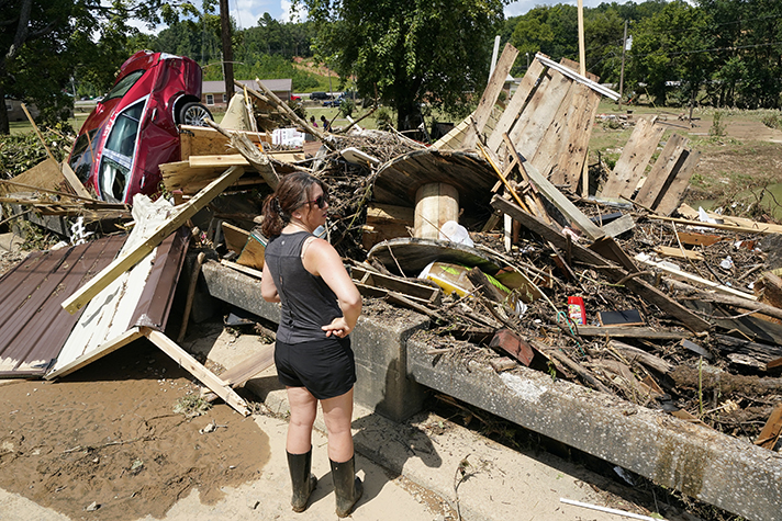 Woman standing in front of debris, wrecked car