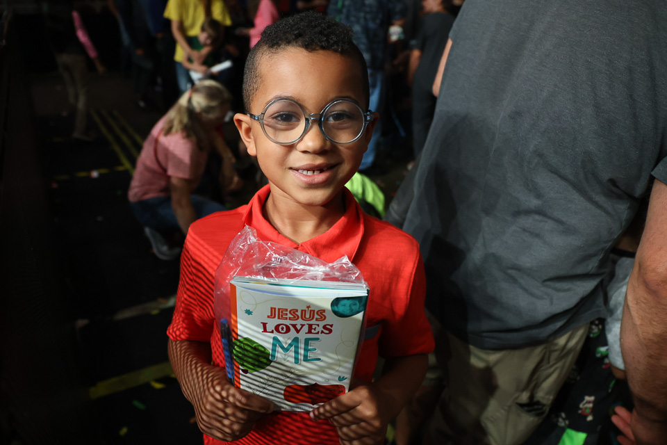 boy holds "Jesus Loves Me" book