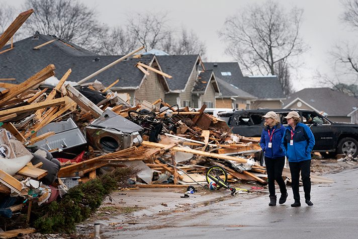 women next to destroyed home