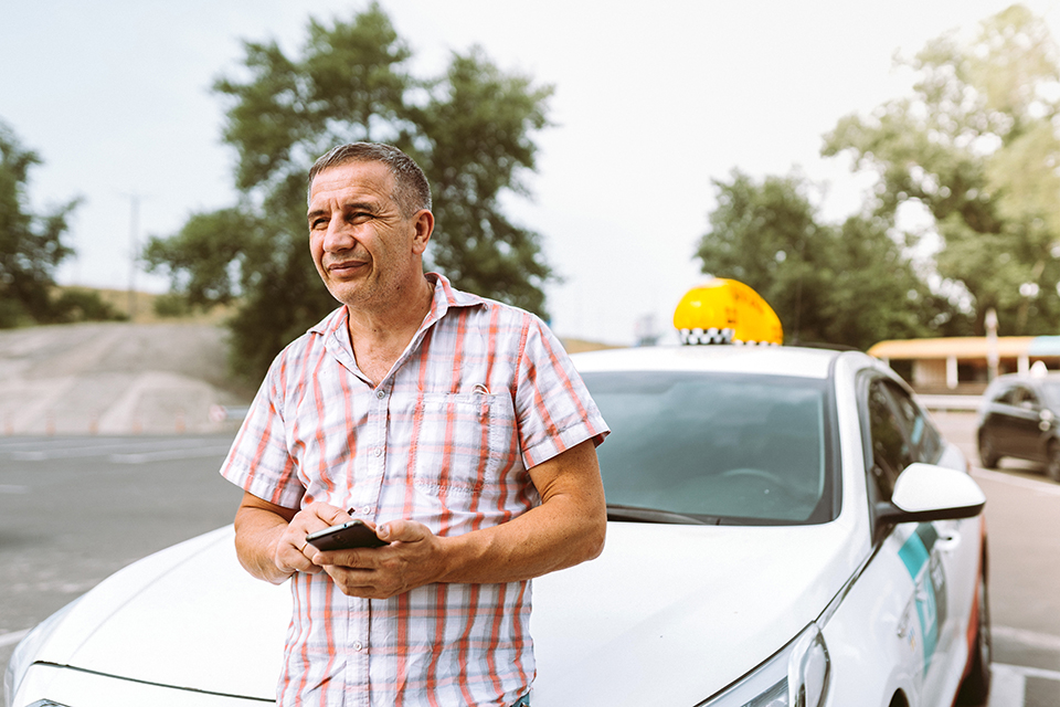 Man in front of car touching phone.