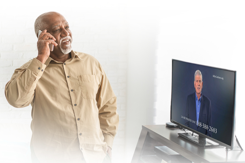 Man talking on phone while standing in front of TV.
