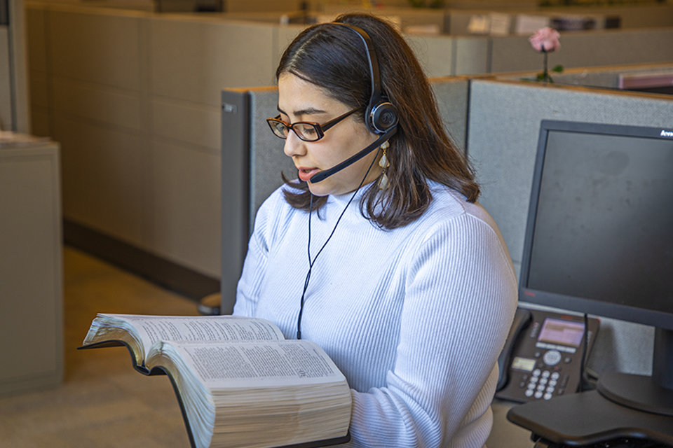 Call center woman with headset reading a Bible passage.