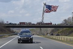 The hearse carrying the body of Billy Graham passes an American flag as it leaves Hickory, N.C., as it drives toward the Billy Graham Library Saturday, Feb. 24, 2018. Graham's body was brought to his hometown of Charlotte on Saturday, Feb. 24, as part of a procession expected to draw crowds of well-wishers. (AP Photo/Kathy Kmonicek, Pool)