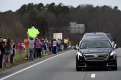 People watch as the hearse carrying the body of Billy Graham near Hickory, N.C., as it drives toward the Billy Graham Library Saturday, Feb. 24, 2018. Graham's body was brought to his hometown of Charlotte on Saturday, Feb. 24, as part of a procession expected to draw crowds of well-wishers. (AP Photo/Kathy Kmonicek, Pool)