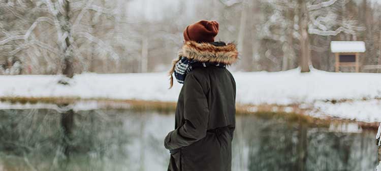 γυναίκα που στέκεται δίπλα σε μια λίμνη το χειμώνα καταθλιπτική