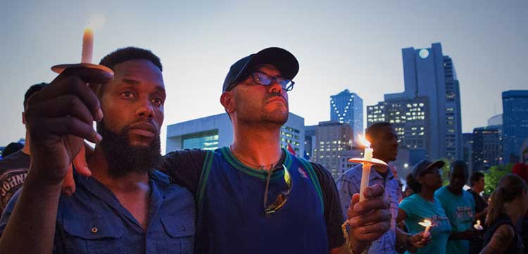 two men standing at a vigil with candles